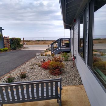 Windrush Inn - Unit Bay porch with blue park bench overlooking the road and ocean. - Hotels Near Me - Cambria, California
