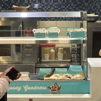 Cinnabon-Carvel - a woman taking a picture of a pastry display - Bakeries Near Me - Charlotte, North Carolina