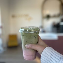 a hand holding a cup of green tea a hand holding a cup of green tea