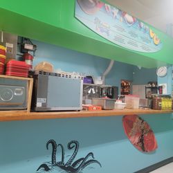 Captain K - The ordering counter currently filled with microwaves toasters scales uncooked food and giant jars of peppers Etc