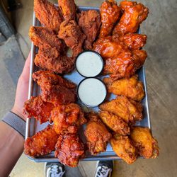 Dog Haus - A tray filled with assorted Dog Haus chicken wings including dry rub and sauced styles, served with ranch, showing crispy tex...