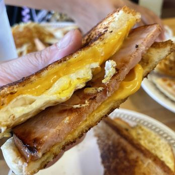 Waffle House - a hand holding a half eaten sandwich - Breakfast & Brunch Near Me - Roanoke Rapids, North Carolina
