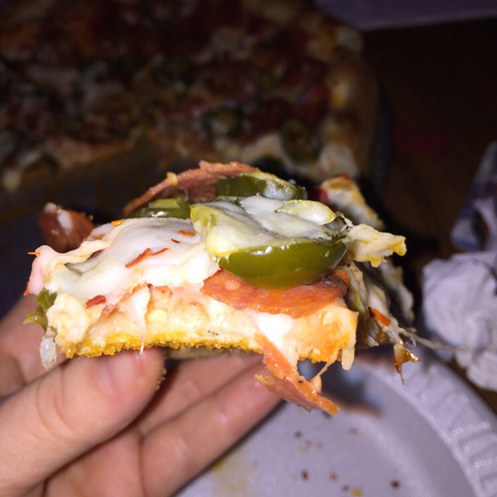 B & J's Pizza - a hand holding a slice of pizza - Pizza Near Me - Rancho Cucamonga, California