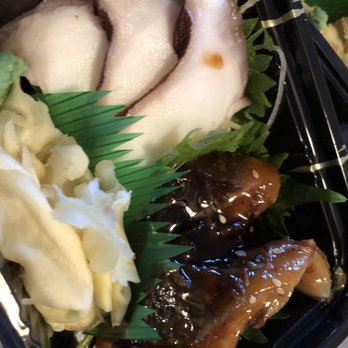 Osaka - Raw fish slices, likely sashimi, are arranged with garnishes and a sauce in a black takeout container, with green leaf accents. - Japanese Near Me - Pawtucket, Rhode Island