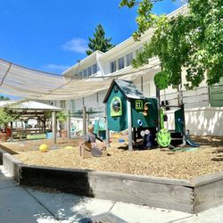 Large, clean preschool playground with monkey bars, play structure, sandbox, water stations, tricycles, etc.