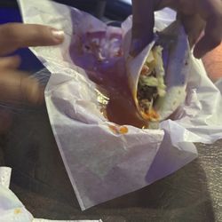 The Munch Bar - Lifting up the taco with the grease dripping out and grease underneath it.