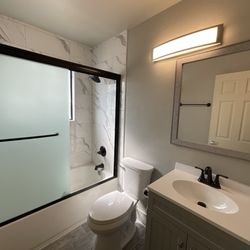 Noor Construction - From marble tile in the shower to wood-look floors, this bathroom remodel blends elegance and durability.