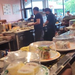 Chefs make the sushi in the middle of conveyor. Chefs make the sushi in the middle of conveyor.