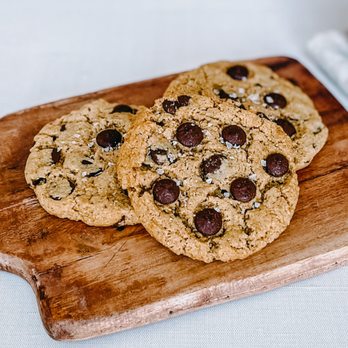 Bell Bottom Bakery - two chocolate chip cookies on a cutting board - Desserts Near Me Bell Bottom Bakery - two chocolate chip cookies on a cutting board - Desserts Near Me