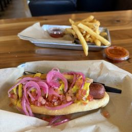 Hot dog with condiments in the front and french fries in the back