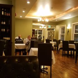 Frasers Gourmet Hideaway - Dining room. Hardwood floor, white table clothes, and comfy chairs