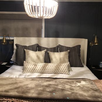Helping Hands Cleaning Services - They do change your linens and your towels... Great job - A bed with a white headboard, several decorative pillows, and a plush blanket is shown in a contemporary bedroom setting. - Home Cleaning Near Me - Elmhurst, Illinois