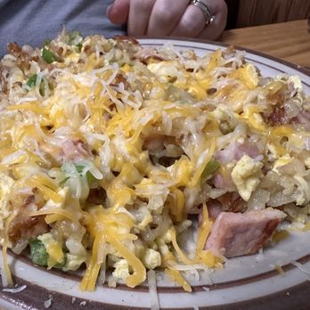 AJ's Cafe - Western Scramble. - A serving of hash brown casserole with shredded cheese, scrambled eggs, ham, and green onions on a ceramic plate. - Cafes Near Me - Omaha, Nebraska