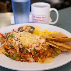 Carnitas Hash: pulled pork, hash browns, tomatoes, peppers, onions, and carrots topped with chihuahua cheese, two eggs, tortilla chips