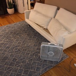 Observe the immaculate area rug, freshly restored couch, and fan.
