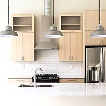 Alpha Constructions & Renovations - a kitchen with white countertops and light wood cabinets - General Contractors Near Me