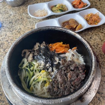 Korean Grill - Dolsot bibimbap - A traditional Korean bibimbap served in a hot stone bowl with mixed vegetables, beef, and seaweed, with side dishes of kimchi, pickled vegetables, and rice. - Korean Near Me - Austin, Texas