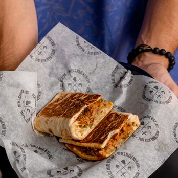 Clean Eatz - a person holding a sandwich in a wrapper - New American Near Me - Fayetteville, North Carolina Clean Eatz - a person holding a sandwich in a wrapper - New American Near Me - Fayetteville, North Carolina