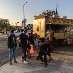a group of people standing in front of a food truck a group of people standing in front of a food truck