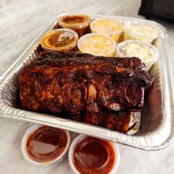 Stubbys Red Wagon BBQ - Full rack of ribs cut in half with two sides of coleslaw two sides of mac & cheese, and two sides of beans