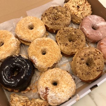 Dough - Clockwise: Toasted Coconut, Cafe au Lait, Dulce de Leche with Almond, Plain Glazed, and a solitary Salted Caramel Chocolate - Desserts Near Me - New York, New York