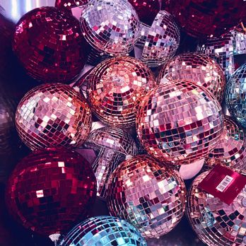Five Below - Shiny disco balls - Multiple disco ball ornaments in red, silver, and pink are displayed together, featuring mirrored surfaces that reflect light and create a sparkling effect. - Discount Store Near Me - Frisco, Texas