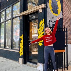 Free Mvmt Shop - Wearing their signature "Exercise Your Rights" motto on a red cropped sweatshirt outside their door!