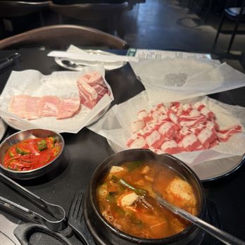 Seoul Meat Co - Spicy cucumber kimchi, tofu soup, pork jowl, pork belly and darker red fatty meat is beef belly. - Korean Near Me - Kirkland, Washington