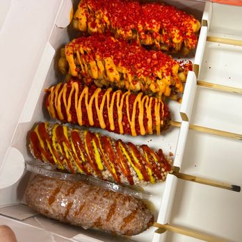 Two Hands Corn Dogs - from left to right or bottom to too Injeolmi Dog Crispy Rice Dog Spicy Dog Potato Dog x2 - Korean Near Me - Tucson, Arizona