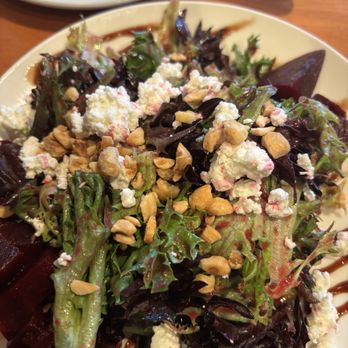 Bluestone Restaurant  - Beet salad - A salad with mixed greens, crumbled cheese, chopped nuts, and a drizzle of dressing, served on a white plate. - American Near Me - Timonium, Maryland