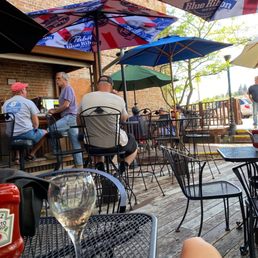 people sitting at tables with umbrellas people sitting at tables with umbrellas