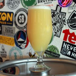 Distant Brewing - One of our haziest hazies, Opaque, in front of our sticker wall at the brewery.