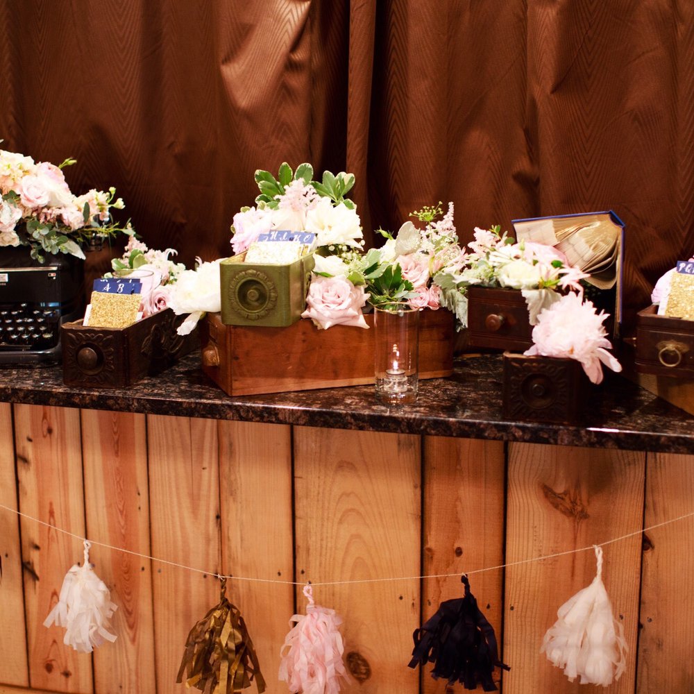 Kio Kreations - Kio used these amazing boxes and florals to create this display for our place cards that were made from library register cards. - Graphic Design Near Me