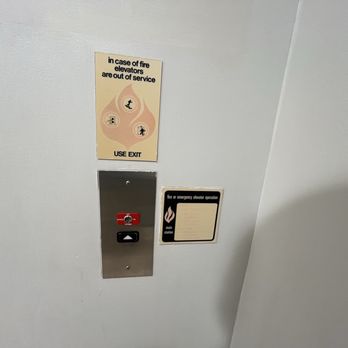 Macy's - A fire alarm pull station and an emergency elevator operation panel are mounted on a white wall, with safety instructions above. - Department Stores Near Me - Virginia Beach, Virginia