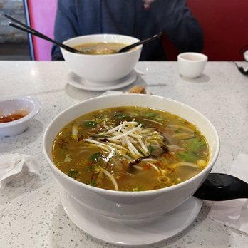 Pho Lee - a man sitting at a table with a bowl of soup - Vietnamese Near Me - London, Ontario