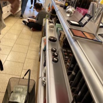 The Cosmetics Company Store - Sales associate on the floor behind the register, using her phone. - Cosmetics & Beauty Supply Near Me - Livermore, California
