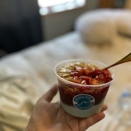 a hand holding a bowl of fruit