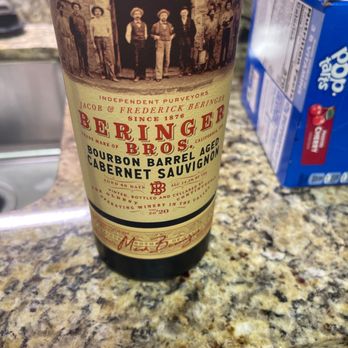 Red Wagon - A bottle of Beringer Brothers Cabernet Sauvignon, featuring a vintage label with historical imagery and text, is positioned on a speckled granite countertop. The label indicates it is a bourbon barrel-aged wine from California. To the right, a blue box of Pop-Tarts is partially visible, suggesting a kitchen or pantry setting. - Tobacco Shops Near Me - Troy, Michigan