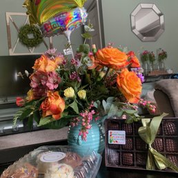 Roses in a pitcher with cupcakes and chocolates
