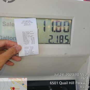 Arco - a hand holding a receipt in front of a gas pump - Gas Stations Near Me - Irvine, California