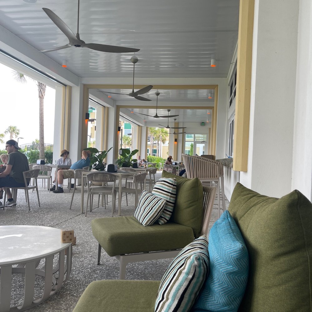 a patio area with green couches and a ceiling fan a patio area with green couches and a ceiling fan