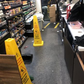 Wawa - Trashy entrance - A store entrance with shelves on the left, a counter on the right, and caution signs on the floor indicating wet floors and potential hazards. - Convenience Stores Near Me - Hanover, Maryland