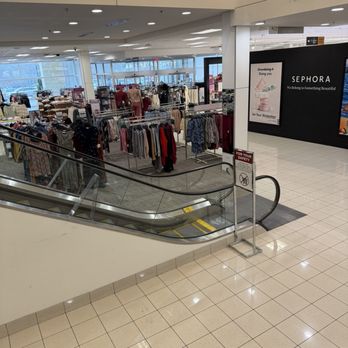 Kohl's - Downstairs shopping area - Inside a department store, clothing racks display various garments, with mannequins dressed in outfits, and large windows in the background. - Department Stores Near Me - APEX, North Carolina