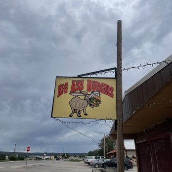 Big Ass Burgers - Almost missed it, it was so small! - A rectangular sign for Big Ass Burgers shows a donkey holding a burger, mounted on a wooden pole outside a restaurant. - Fast Food Near Me - Thoreau, New Mexico