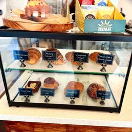 Pastries - A bakery display case contains croissants, bread, and pastries, with labels and prices. The case showcases butter, chocolate, cream cheese, and spinach croissants.
