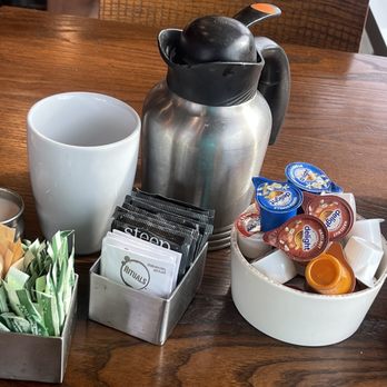 First Watch - My small Tea setup complete with sugars, variety tea, Hot Water canister, variety creamers, and small oat milk... - Breakfast & Brunch Near Me - Wilmington, North Carolina