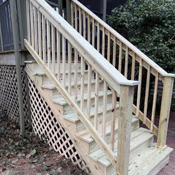 Finey Home Improvement - A wooden outdoor staircase with handrails on both sides and lattice skirting underneath, leading up to a deck or porch. - Decks & Railing Near Me - Rockland, Massachusetts