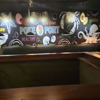PokePort Temecula - The image shows a dining area with a dark ceiling, hanging light fixtures, and a mural wall decorated with seafood illustrations and the restaurant name 'Poke Port.' - Poke Near Me - Temecula, California
