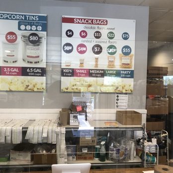 Cornucopia Popcorn - A menu board at Cornucopia Popcorn in Austin, TX, shows prices for popcorn tins and snack bags, with options for different sizes and flavors. - Popcorn Shops Near Me - Austin, Texas