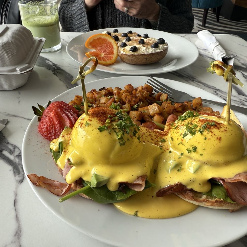 Surf Point Coffee House - Eggs, Benedict and blueberry morning bagel in the back ground. - Breakfast & Brunch Near Me - Shelter Cove, California Surf Point Coffee House - Eggs, Benedict and blueberry morning bagel in the back ground. - Breakfast & Brunch Near Me - Shelter Cove, California